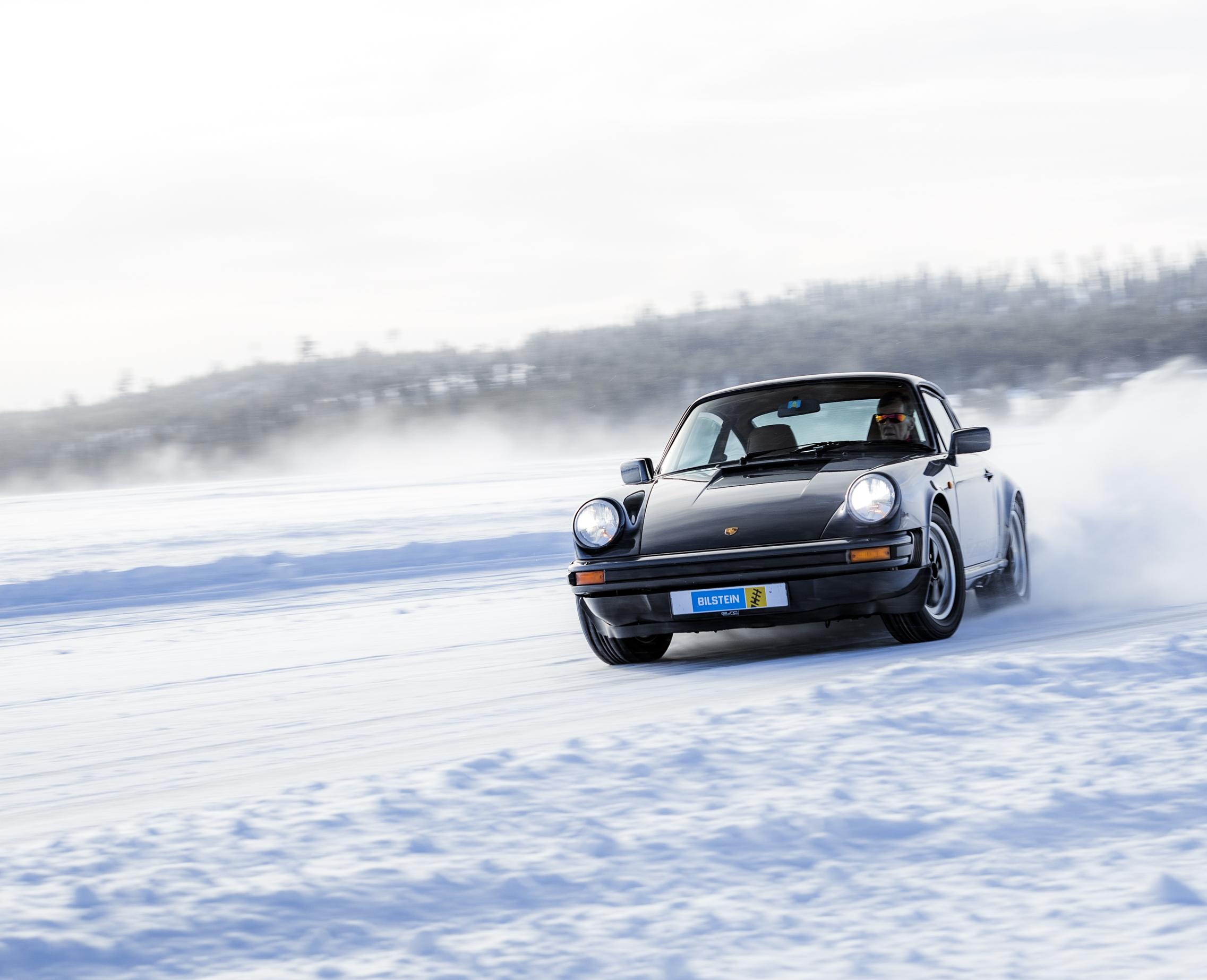 Walter Röhrl driving a black Porsche Oldtimer on a frozen lake in Sweden